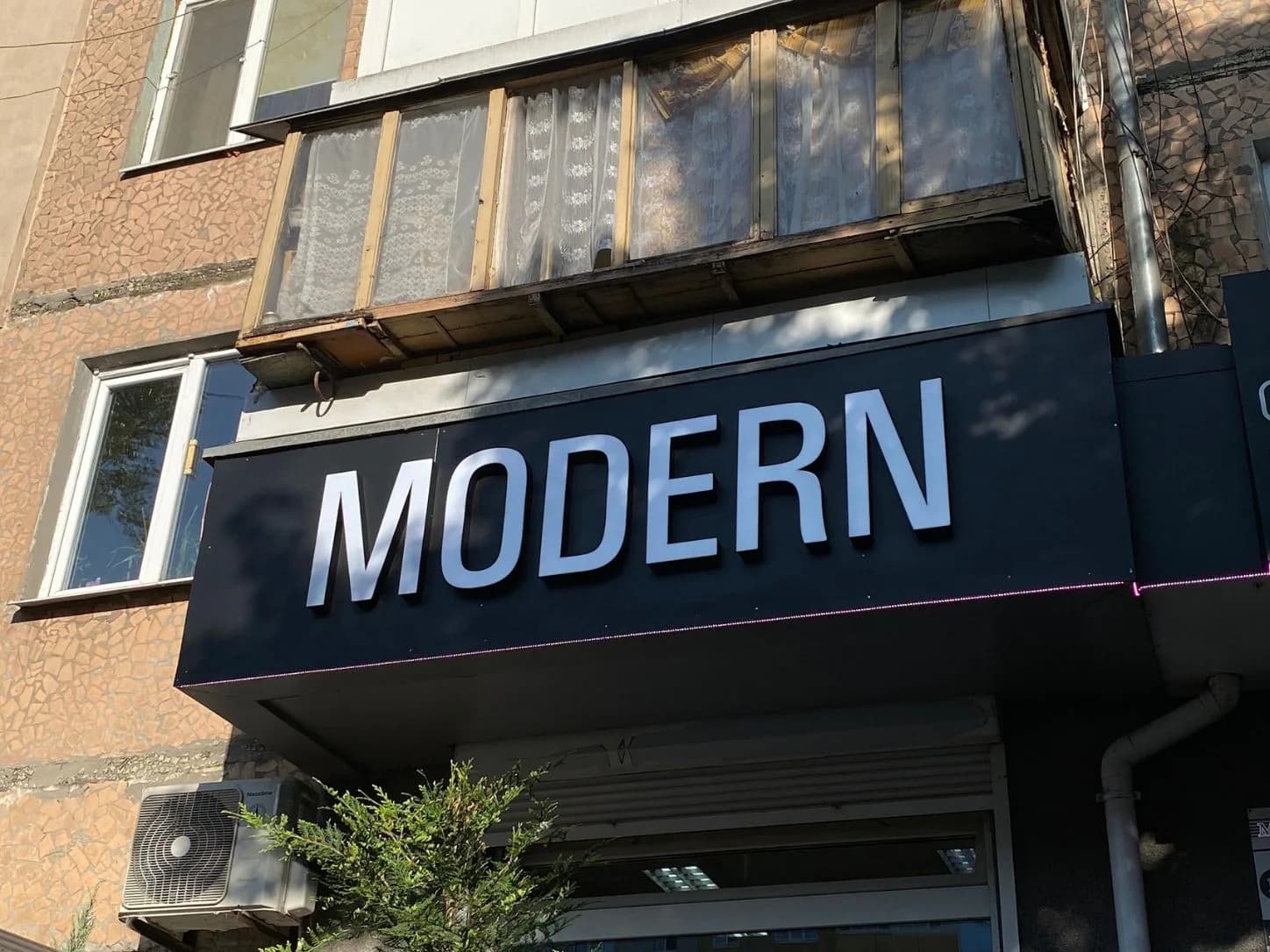 Крупний план фасадної вивіски MODERN зі світлими об’ємними літерами на темній панелі
