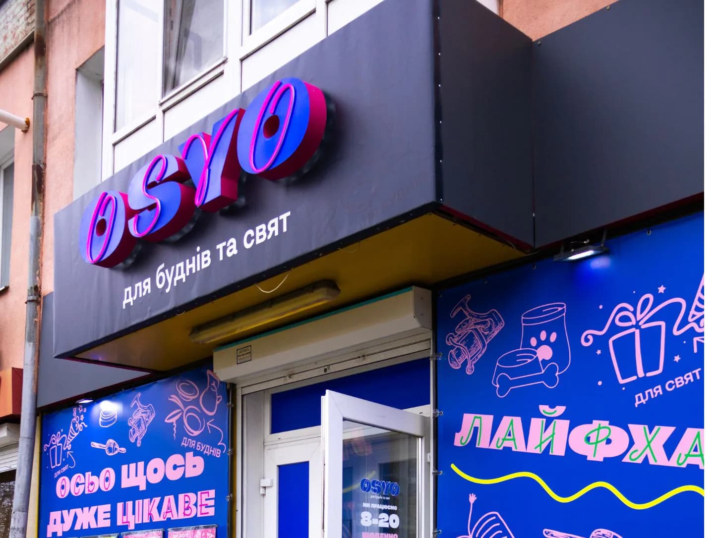 Бічний ракурс фасаду OSYO з об’ємними літерами та банерним оформленням