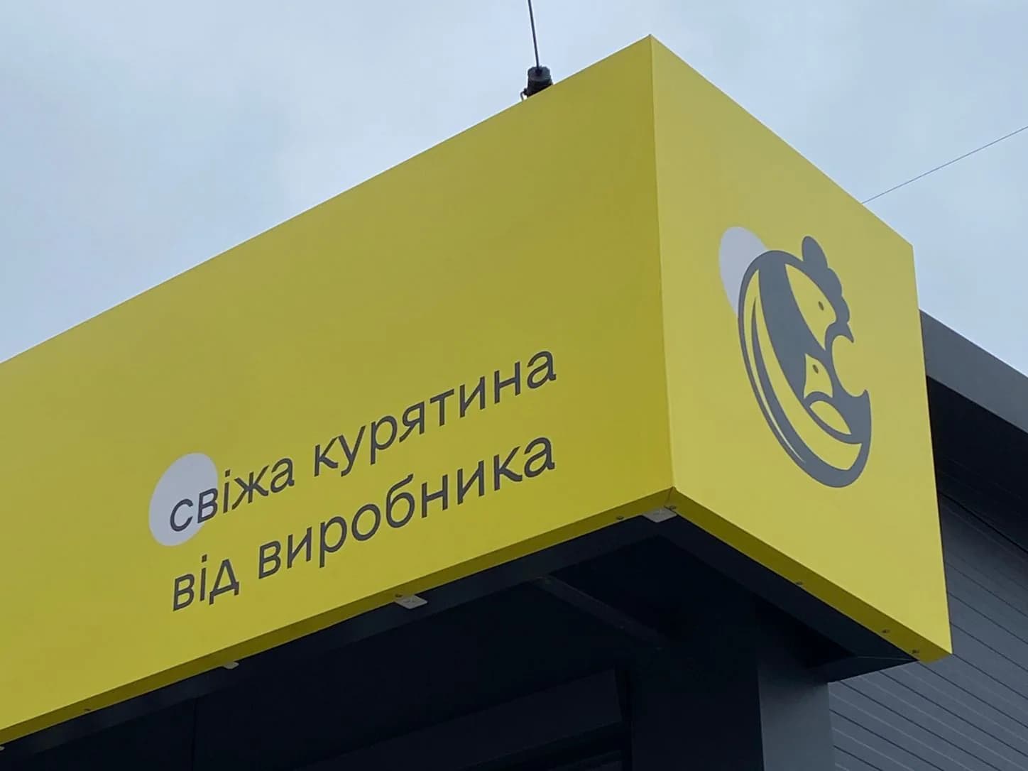 Кутовий фасад «Щасливого курчати» з написом про свіжу курятину та логотипом