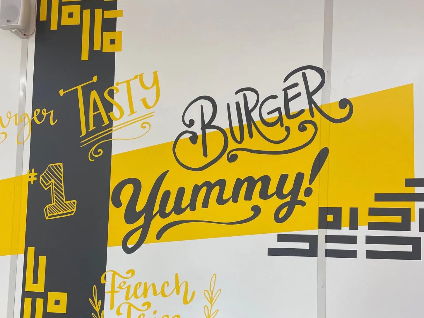 Жовто-чорна настінна графіка в інтер’єрі закладу Tasty