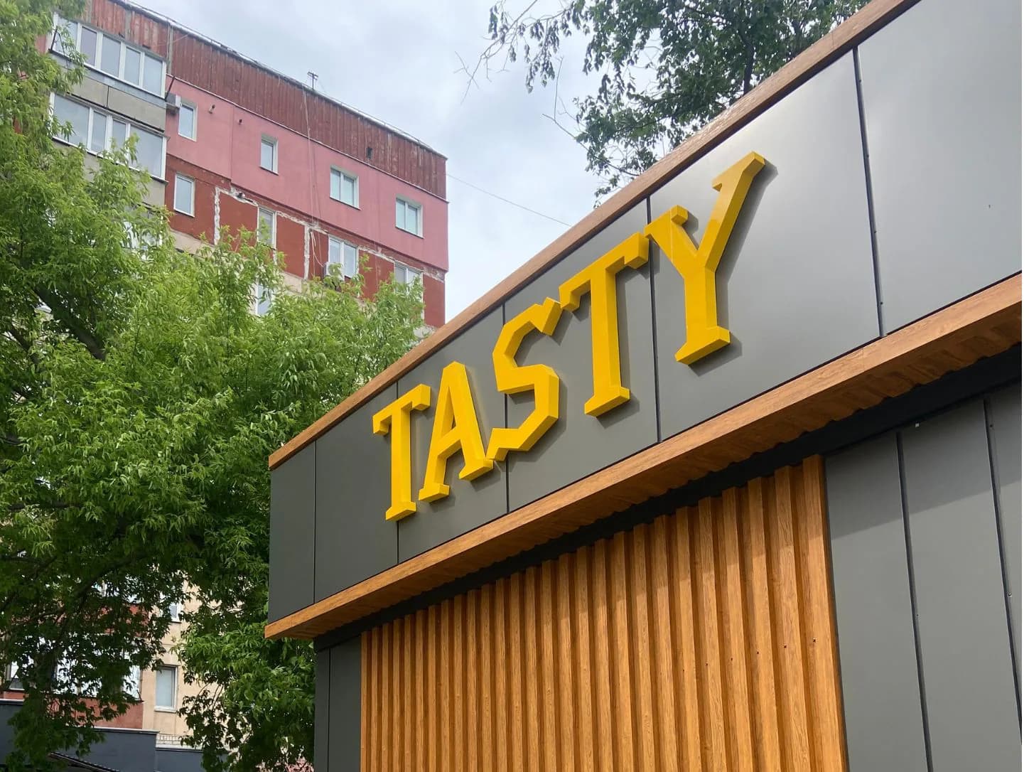 Фасад закладу Tasty з жовтими об’ємними літерами та оформленими входами